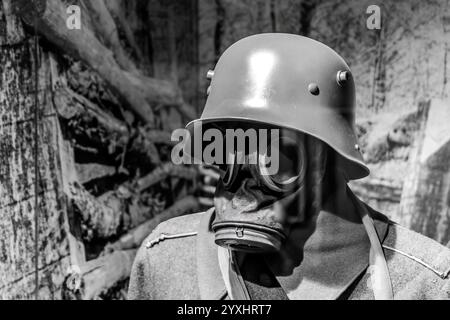 Primo piano di un soldato della prima guerra mondiale che indossa una maschera a gas e un casco in bianco e nero, equipaggiamento militare storico, scena di trincea in tempo di guerra, spaventosa inquietudine Foto Stock