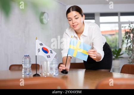 Donna d'affari che organizza le bandiere della Corea del Sud e della Svezia per la presentazione e i negoziati Foto Stock