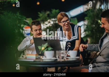 Uomini d'affari che hanno una riunione produttiva all'aperto con risate e conversazioni. Tre colleghi si sono impegnati in una discussione positiva circondata da Foto Stock
