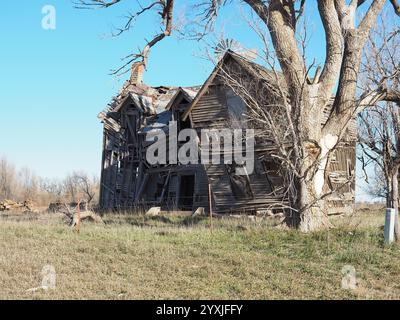 Una grande fattoria abbandonata che crolla con l'età, circondata dalle praterie dorate delle Flint Hills nel Kansas centrale durante l'autunno Foto Stock