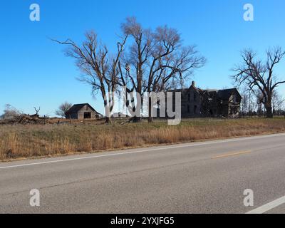 Una grande fattoria abbandonata che crolla con l'età, circondata dalle praterie dorate delle Flint Hills nel Kansas centrale durante l'autunno Foto Stock