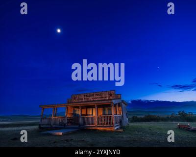 Il quarto di luna, Venere e Marte nel cielo crepuscolo sopra una capanna vicino a Lundbreck, Alberta, Canada. Foto Stock