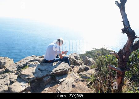 Sestri Levante, Italia - 10 novembre 2024. Escursioni in montagna. Persone in abiti sportivi con zaini, che riposano sulla roccia. Foto Stock