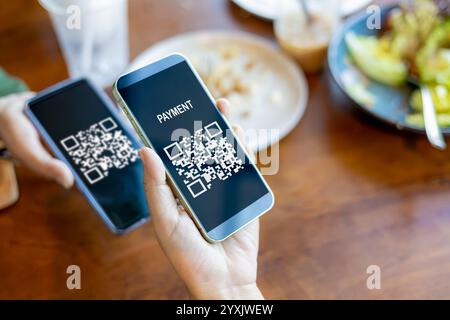 Mani che tengono il telefono cellulare, mano che utilizza l'applicazione per telefono cellulare per la scansione del codice QR, pagamento con codice QR o concetto di tecnologia senza contanti, accettazione bar Foto Stock