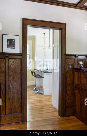 Cucina bianca ristrutturata di recente vista attraverso la porta della sala da pranzo con scodellino in legno scuro Foto Stock