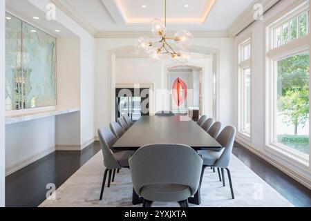Sala da pranzo bianca con arte moderna e grandi finestre Foto Stock