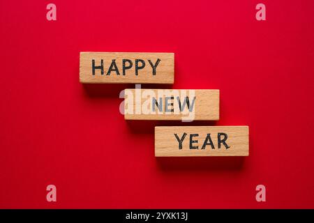 Felice anno nuovo scritto su blocchi di legno su sfondo rosso Foto Stock