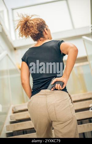 DONNA CON UNA PISTOLA, VISTA POSTERIORE Foto Stock