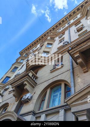 La facciata di un edificio classico mostra crepe e modifiche irregolari. Questa immagine sottolinea le conseguenze della negligenza e della non regolamentazione urbana Foto Stock