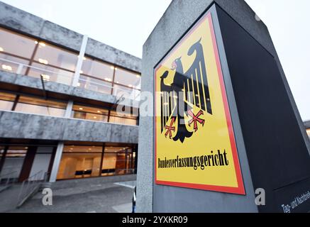 Karlsruhe, Germania. 17 dicembre 2024. Un cartello con un'aquila federale e le parole "Corte costituzionale federale” si trovano di fronte all'edificio del tribunale. Il secondo Senato sta ascoltando argomenti orali sulle missioni dei droni statunitensi tramite Ramstein. Il caso riguarda una denuncia costituzionale contro l'uso della base aerea di Ramstein per missioni con droni da parte delle forze armate statunitensi all'estero. I denuncianti sono due yemeniti i cui parenti sono stati uccisi in una missione drone statunitense nella loro città natale nel 2012. Crediti: Uli Deck/dpa/Alamy Live News Foto Stock