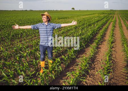 Portrait of happy farmer in his corn field. Successful farmer standing in agricultural field with arms outstretched. Foto Stock