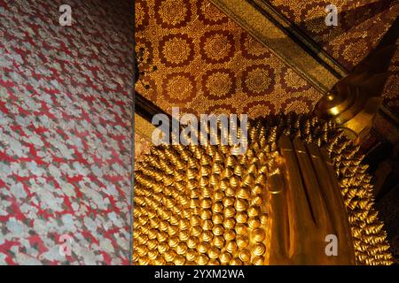 Bangkok, Thailandia - 29 novembre 2024: Mano e retro della testa della statua dorata del buddha reclinato al tempio wat Pho Foto Stock