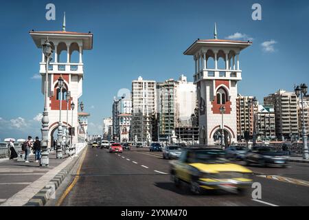 Lo Stanley Bridge di Alessandria, Egitto, è caratterizzato da traffico vivace, architettura elegante e torri iconiche sotto un cielo azzurro. Un moderno punto di riferimento urbano Foto Stock