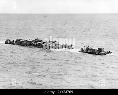 Un traghetto "Rhino" della Marina degli Stati Uniti carico si avvicina alle spiagge dell'invasione della Normandia il 6 giugno 1944. Questo traghetto è RHF-3, con il rimorchiatore "Rhino" RHT-3. Nota il nome "Hell's Angels" sugli scudi della stazione di conning dell'RHT-3. Foto della Guardia Costiera DEGLI STATI UNITI Foto Stock