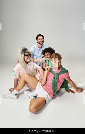 Quattro amici si mettono in posa con gioia in abiti colorati, mostrando il loro orgoglio in uno studio. Foto Stock