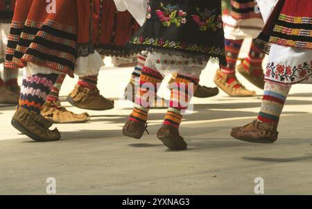 Folklore bulgaro. Le ragazze ballano folk. Le persone in costumi tradizionali ballano le danze popolari bulgare. Primo piano delle gambe femminili con sho tradizionale Foto Stock