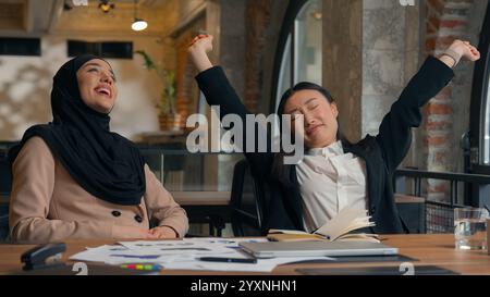 Due donne d'affari multirazziali donna asiatica coreana ragazza musulmana hijab islamico donna d'affari in ufficio sorridente fine videochiamata conferenza portatile Foto Stock
