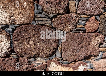 Un muro fatto di rocce di colore brunastro. La parete è fatta di piccole rocce e ha una consistenza ruvida Foto Stock