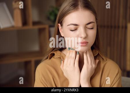 Giovane donna che si autoesamina la ghiandola tiroidea a casa, primo piano Foto Stock