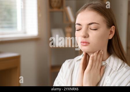 Giovane donna che si autoesamina la ghiandola tiroidea a casa, primo piano Foto Stock