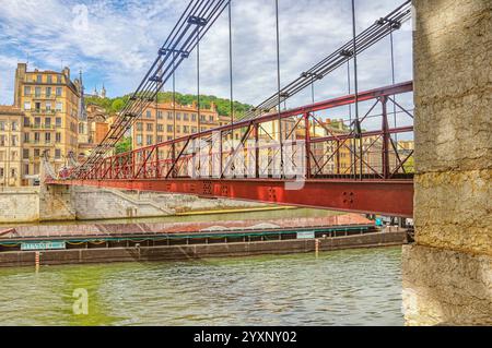 Maestoso commercio fluviale: Grandi chiatte sul Saône e ponte pedonale a Lione Foto Stock