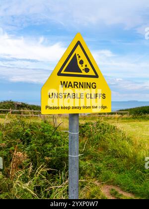 Cartello di avvertimento accanto alle scogliere vicino a Kilve nel nord del Somerset, Inghilterra, dove l'erosione costiera crea cascate rocciose. Foto Stock