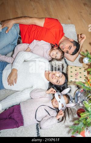 La famiglia ama trascorrere momenti di qualità vicino all'albero di Natale decorato. I bambini srotolano regali, giocano e apprezzano l'atmosfera festosa del Natale Foto Stock