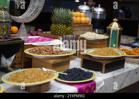 Squisita offerta con piatti colorati di frutta secca e noci, splendidamente allestiti con decorazioni vivaci e frutta tropicale fresca all'iftar Foto Stock