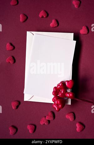 Busta e cuori rossi su sfondo rosso. Vista dall'alto. San Valentino. Foto Stock