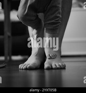 I piedi del neonato sui piedi del papà sono piccoli e grandi. Foto di alta qualità Foto Stock