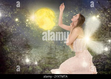 Incantevole fata nella foresta scintillante con luci magiche sotto la luna piena. Bella ragazza con le ali Foto Stock