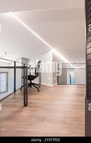 Elegante loft per uffici con una moderna sedia ergonomica, grande pavimento in legno ed eleganti elementi di design minimalista, perfetto per i prodigi creativi Foto Stock