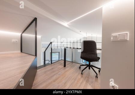 Elegante loft per uffici con una moderna sedia ergonomica, grande pavimento in legno ed eleganti elementi di design minimalista, perfetto per i prodigi creativi Foto Stock