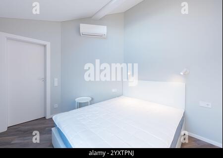 Camera da letto luminosa e pulita, dotata di un comodo letto, armadio a muro bianco, lucernario e design minimalista, atmosfera perfetta per il relax. Min. Moderna Foto Stock