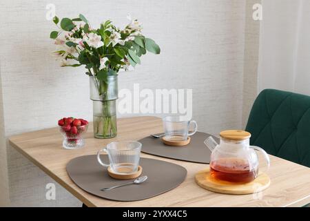 Un intimo e invitante tè con splendidi fiori e fragole fresche e succose Foto Stock