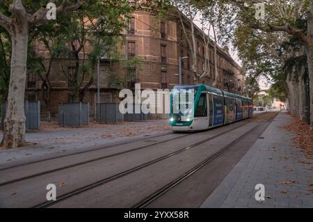 Barcellona, Catalogna, Spagna - 08 04 2023: Tram verde Alstom Citadis della metropolitana leggera di Trambaix di fronte al vecchio edificio a quattro piani sulla Carrer de We Foto Stock