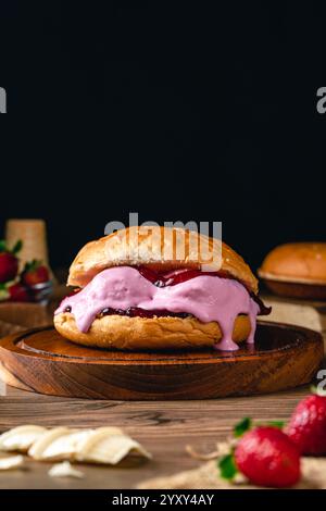 hamburger con gelato alle fragole. Sandwich con gelato su sfondo in legno. Foto Stock