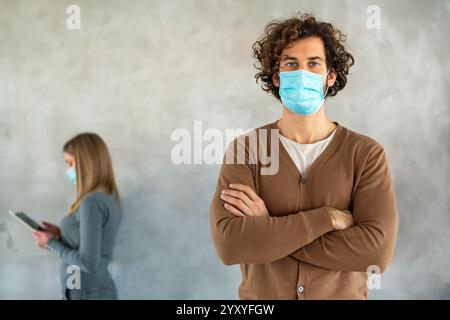 Persone in stile business e maschere mediche in piedi con gadget e mantenere la distanza sociale. Foto Stock