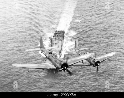 Due bombardieri Douglas SBD-5 Dauntless della US Navy dello Squadron 6 (VB-6) sorvolano la portaerei aicrcaft USS Enterprise (CV-6) il 12 novembre 1943 Foto Stock