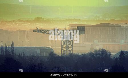 Glasgow, Scozia, Regno Unito. 18 dicembre 2024. Meteo nel Regno Unito: Piovendo nel centro della città si è lasciato il posto a un basso livello di sole all'alba attraverso la nuvola. La gru barclay curle clyde titan olsshipbuilding di fronte all'ospedale della regina elizabeeth accanto al fiume clyde. Credit Gerard Ferry/Alamy Live News Foto Stock