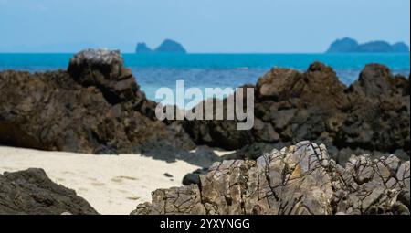 Una spiaggia rocciosa a Koh Samui, Thailandia, caratterizzata da aspre rocce vulcaniche, sabbia soffice e un mare turchese. Foto Stock