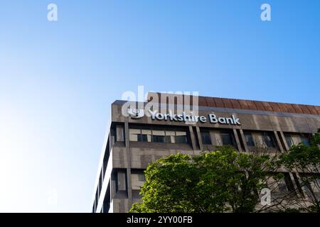 Leeds Inghilterra: 2 giugno 2024: Yorkshire Bank si erge contro un cielo azzurro limpido con vegetazione in primo piano che appare in una giornata di sole Foto Stock