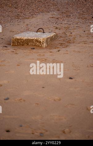 blocco di cemento con manico in metallo arrugginito su una spiaggia sabbiosa a saltburn, nel nord dello yorkshire, inghilterra, regno unito Foto Stock