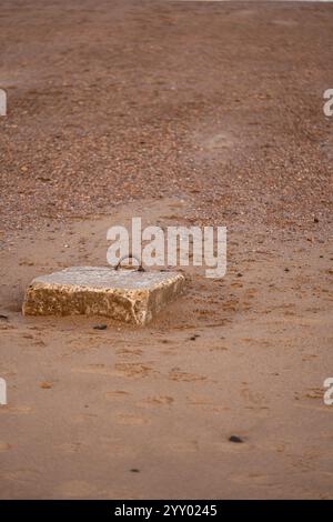 blocco di cemento con manico in metallo arrugginito su una spiaggia sabbiosa a saltburn, nel nord dello yorkshire, inghilterra, regno unito Foto Stock