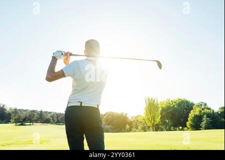 Giocatore di golf maschile che gioca a golf dal tee box allo splendido tramonto Foto Stock