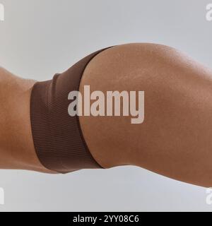 La vista ravvicinata cattura la morbidezza della pelle e la forma armoniosa. Contorni del corpo, dedizione al fitness e fiducia nell'espressione di sé. Foto Stock