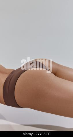 La vista ravvicinata cattura la morbidezza della pelle e la forma armoniosa. Contorni del corpo, dedizione al fitness e fiducia nell'espressione di sé. Foto Stock