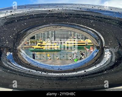 Sydney, Australia. 7 maggio 2024. I traghetti possono essere visti nella metropoli australiana di Sydney presso il terminal dei traghetti di Circular Quay attraverso un'opera d'arte di fronte al Museo di Arte Contemporanea Gli iconici traghetti gialli e verdi fanno parte del porto della città tanto quanto il famosissimo Teatro dell'Opera e il Ponte del Porto. Crediti: Steffen Trumpf/dpa/Alamy Live News Foto Stock
