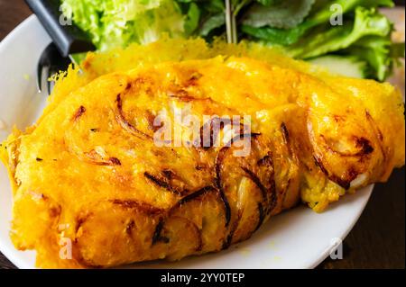 Pancake croccante vietnamita Banh Xeo con erbe fresche e lattuga Foto Stock