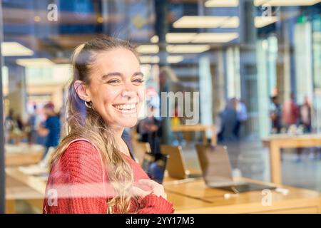 Giovane donna caucasica che naviga su notebook in negozio di elettronica Foto Stock